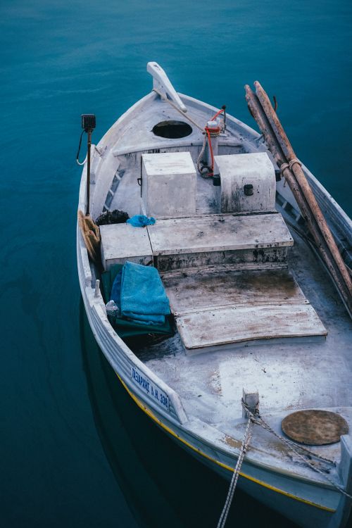 Free A serene fishing boat anchored in calm blue waters, showcasing a tranquil maritime scene. Stock Photo