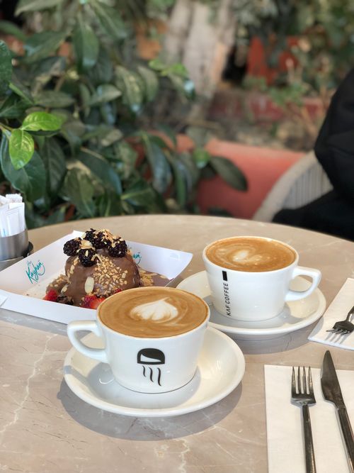 Free A warm café setting with coffee cups and a delicious dessert on the table. Stock Photo