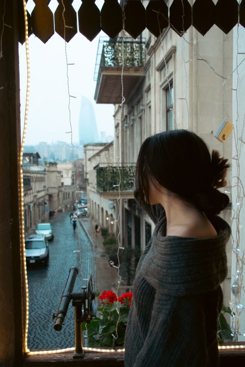 Free Artistic view of a girl looking out over Baku's cobbled streets on a cloudy day. Stock Photo