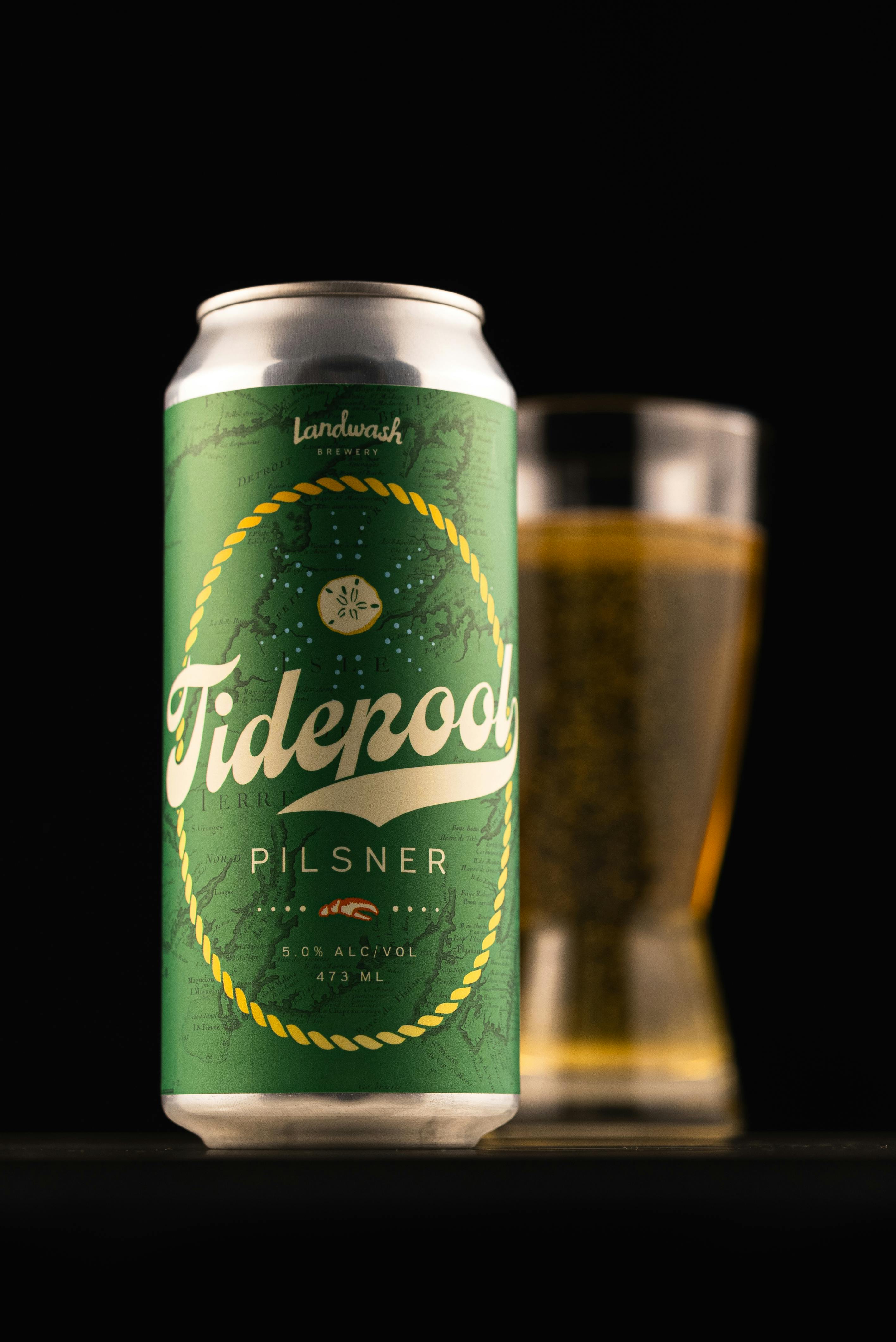 Tidepool Pilsner can and beer glass against dark background. Classic beverage concept.