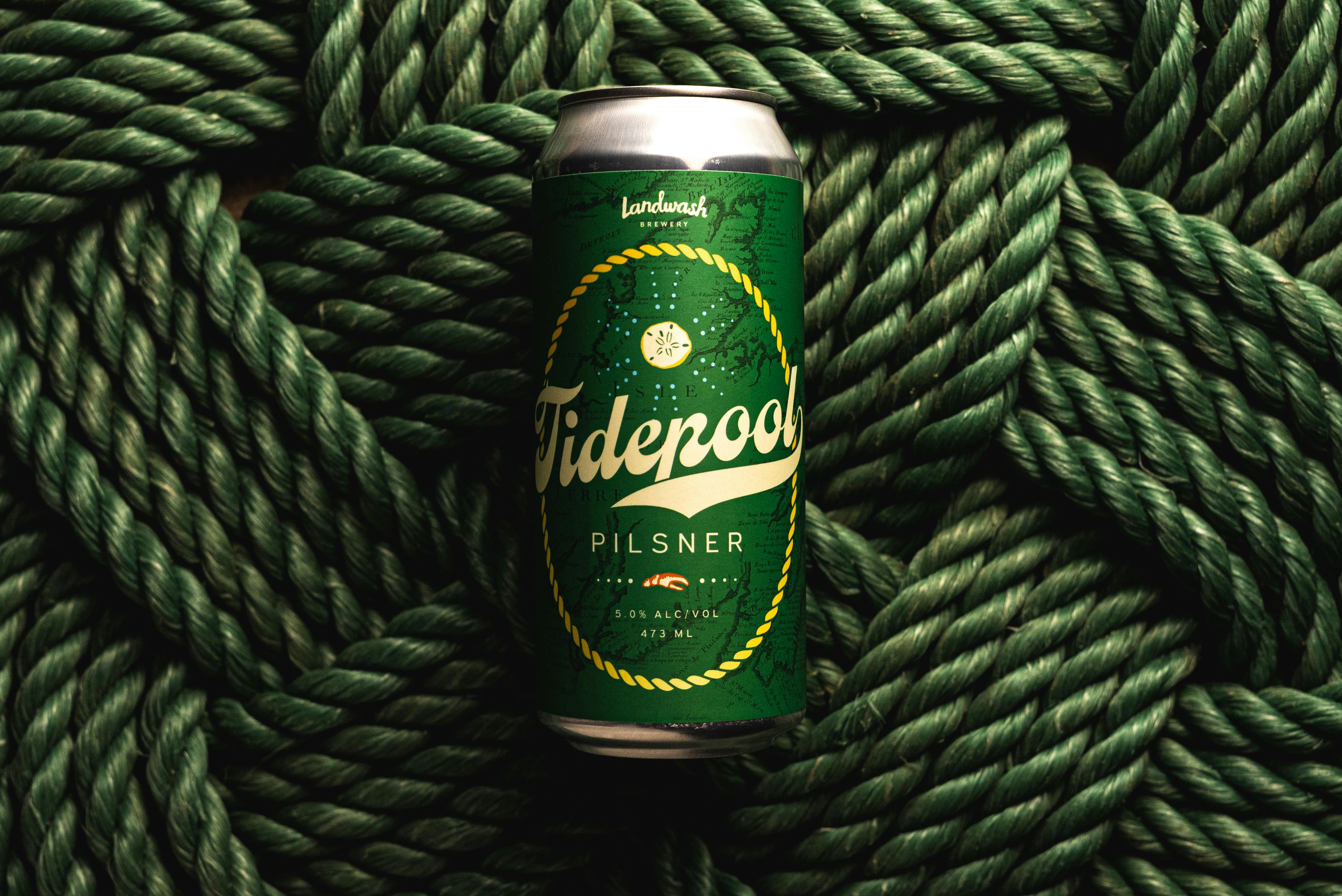 A Tidepool Pilsner beer can placed on intricately woven green nautical rope.