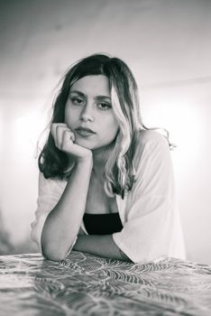 A reflective black and white portrait of a young woman, showcasing subtle emotion and quiet contemplation.