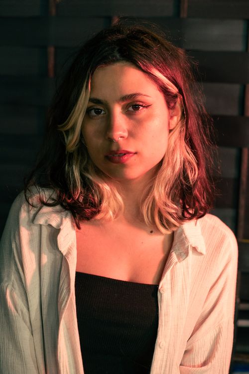 Free A woman with two-tone hair poses against a textured background with gentle lighting. Stock Photo