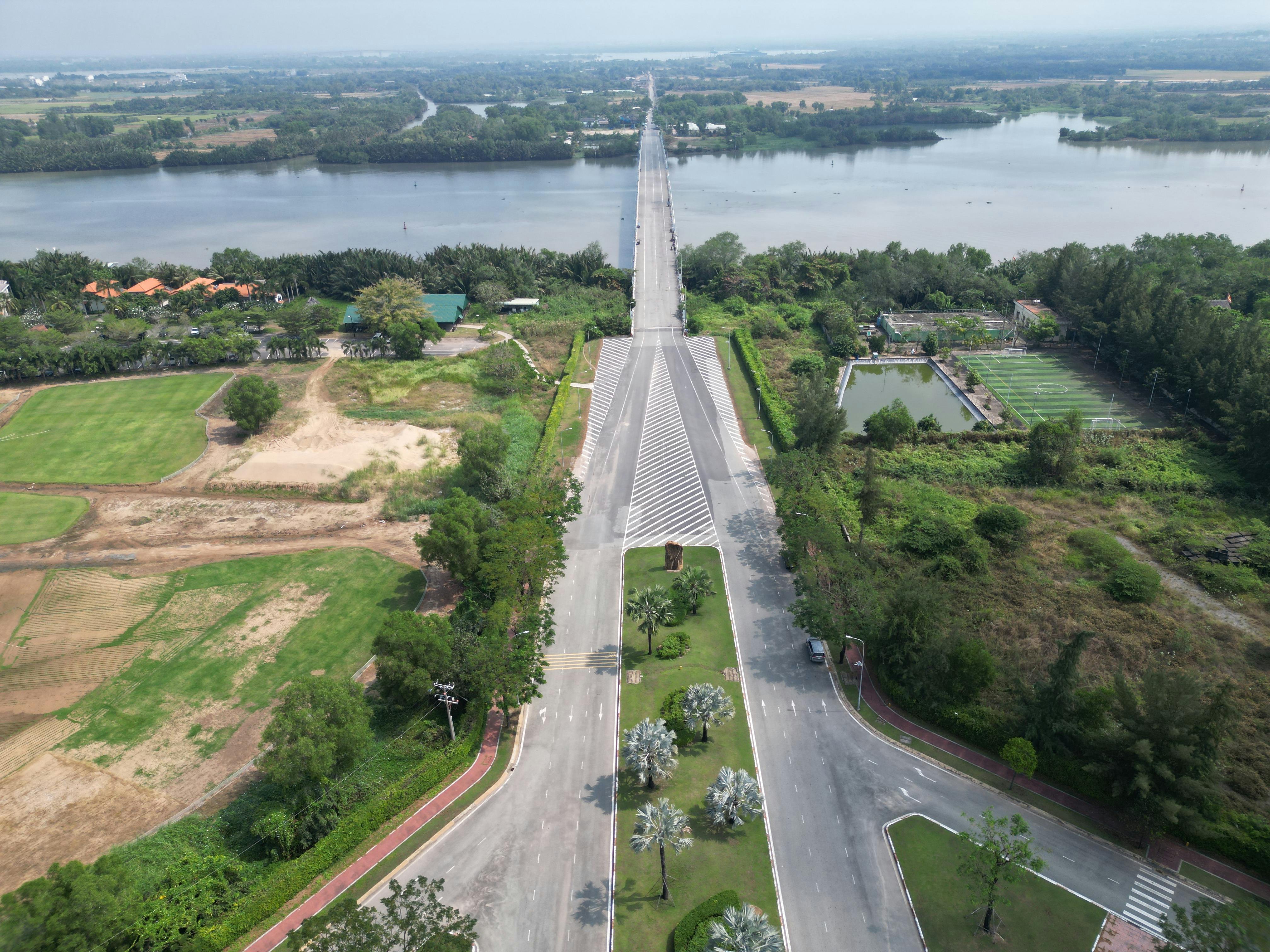 Stunning aerial view of rural road intersecting lush fields by a river.