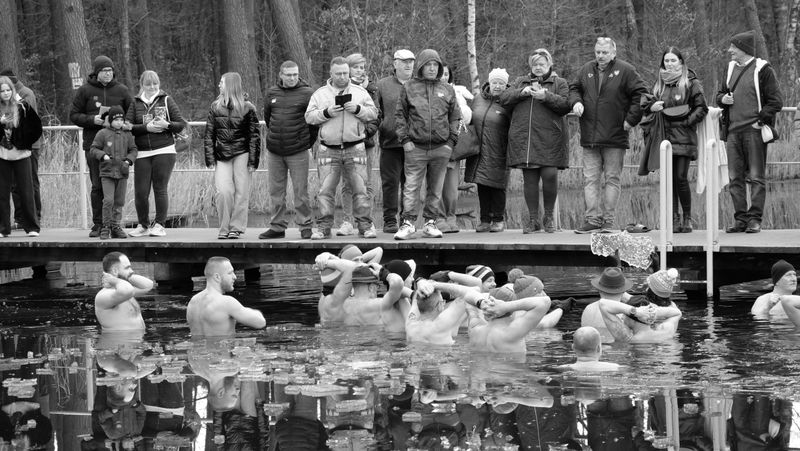Group of people ice swimming together in a cold lake during winter