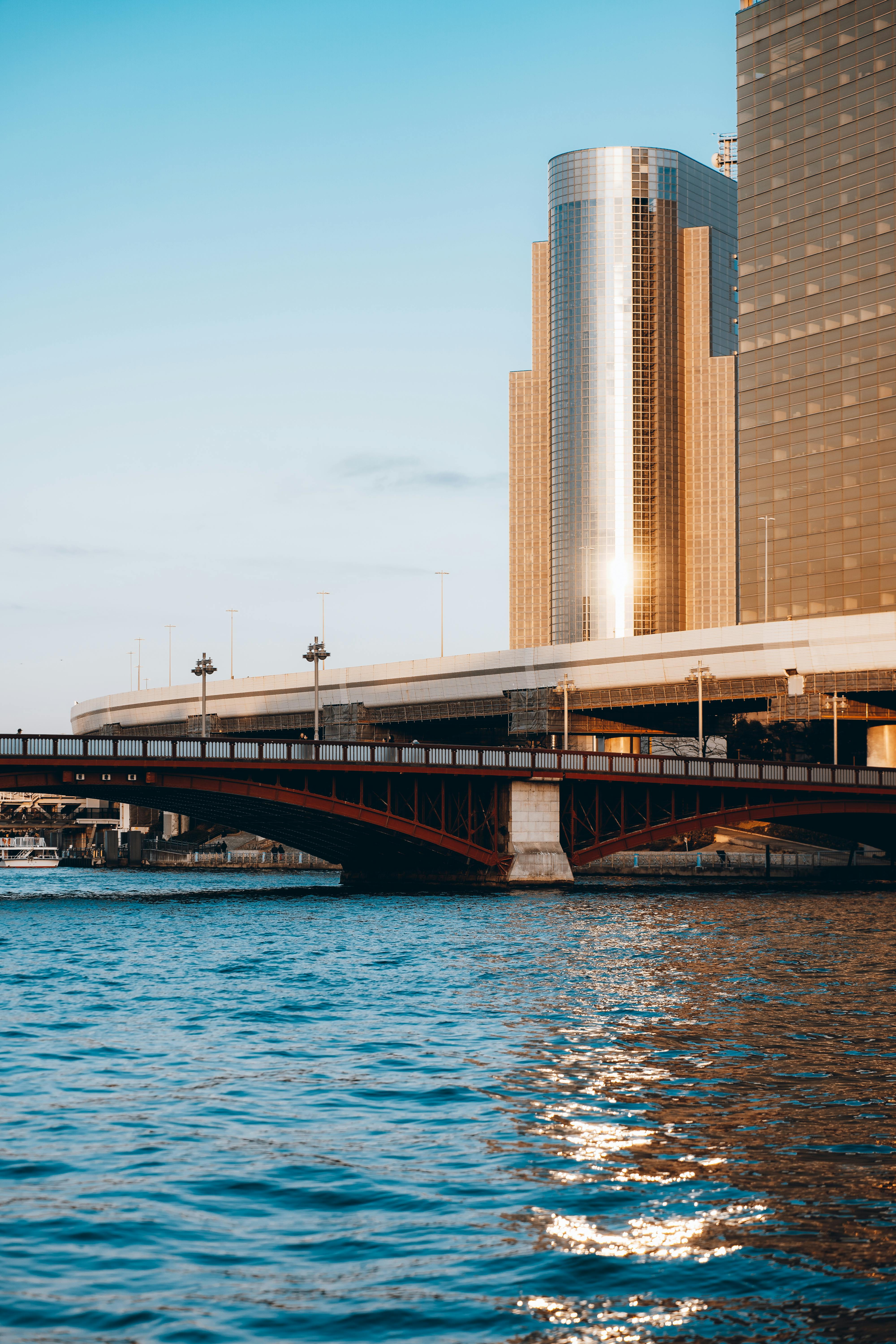 Captured during sunset, this image showcases Tokyo's urban skyline and a vibrant river bridge.