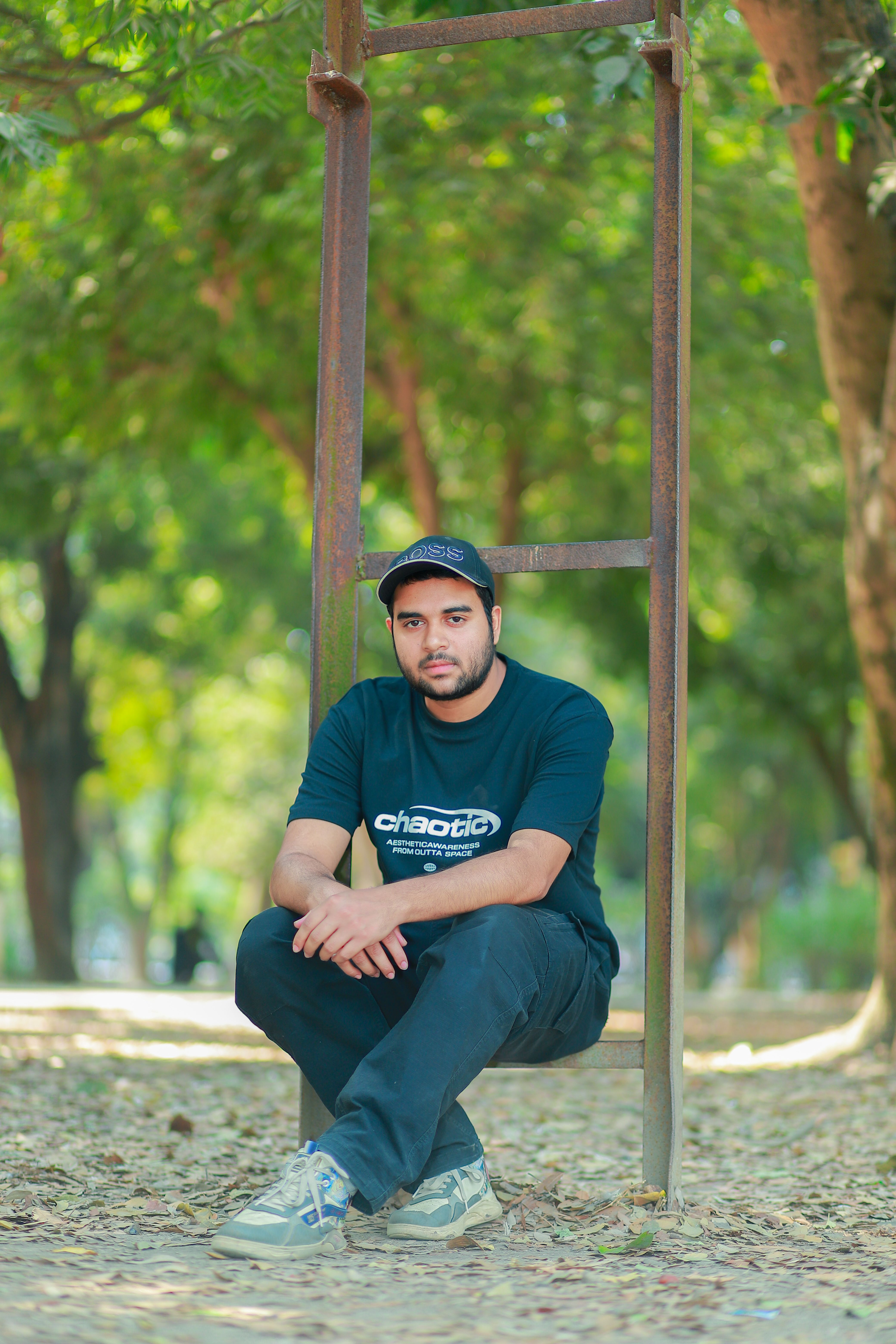 Young man in casual wear sitting outdoors in a serene park in Bangladesh.