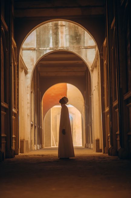 Conceptual silhouette of a person standing in a historic arched corridor in Gombe, Nigeria.