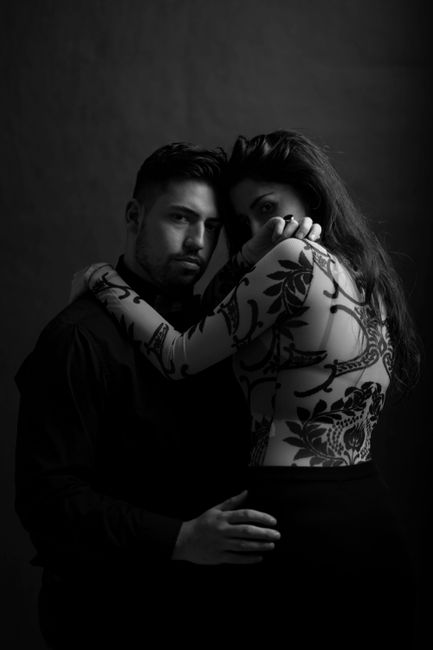 A couple intimately embracing, showcasing fashion and style in a monochrome studio portrait.