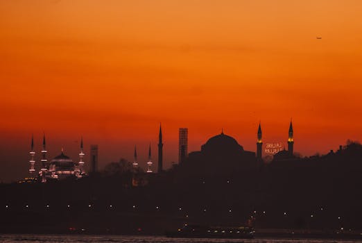 Silhouette of Istanbul landmarks at sunset, highlighting a vibrant orange sky.