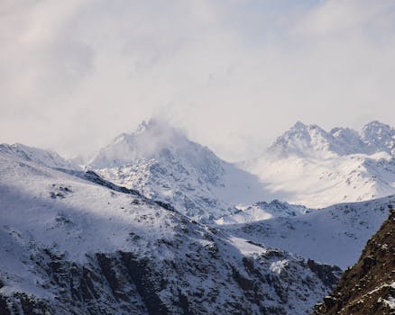 Stunning snowy mountain peaks under cloudy sky, perfect for winter or adventure themes.