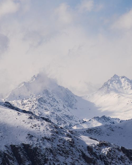 Free Majestic snowcapped mountains with clouds in a serene winter setting. Stock Photo