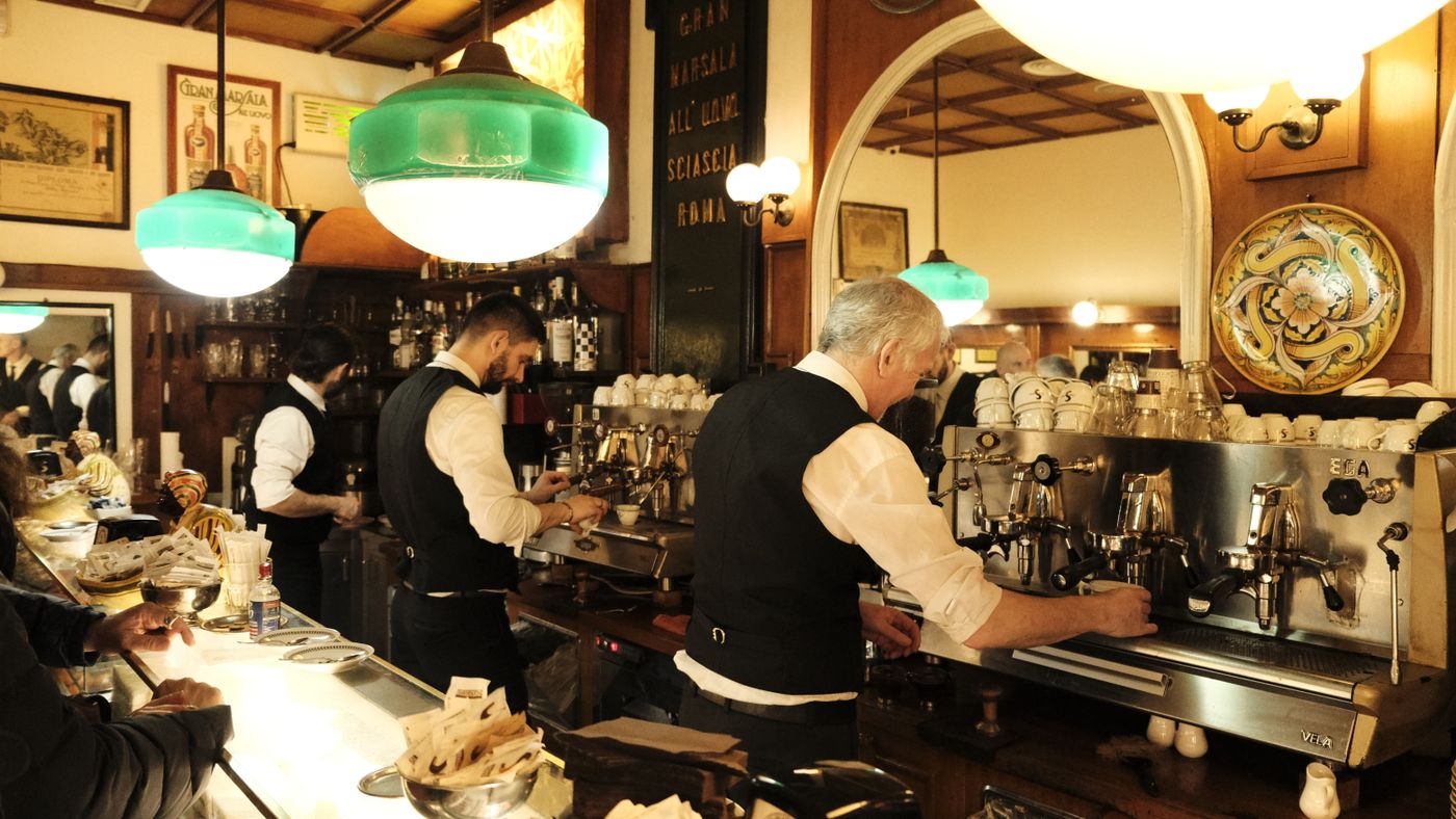 Baristi al lavoro dietro il banco di un bar storico italiano