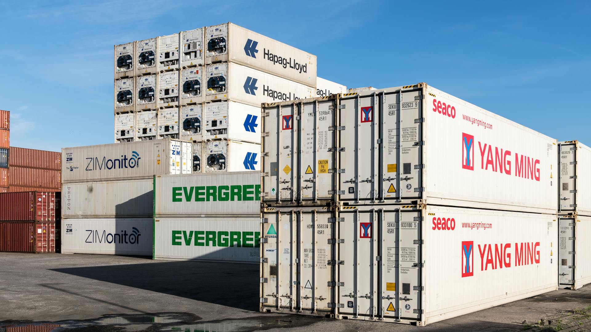 Photograph of stacked shipping containers at a bustling Hamburg port terminal.