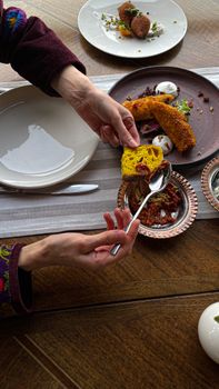 A cozy dining scene with hands selecting fried fish and vibrant side dishes.