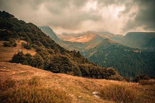 Free Breathtaking view of misty mountains and lush forests under dramatic, cloud-covered skies. Stock Photo