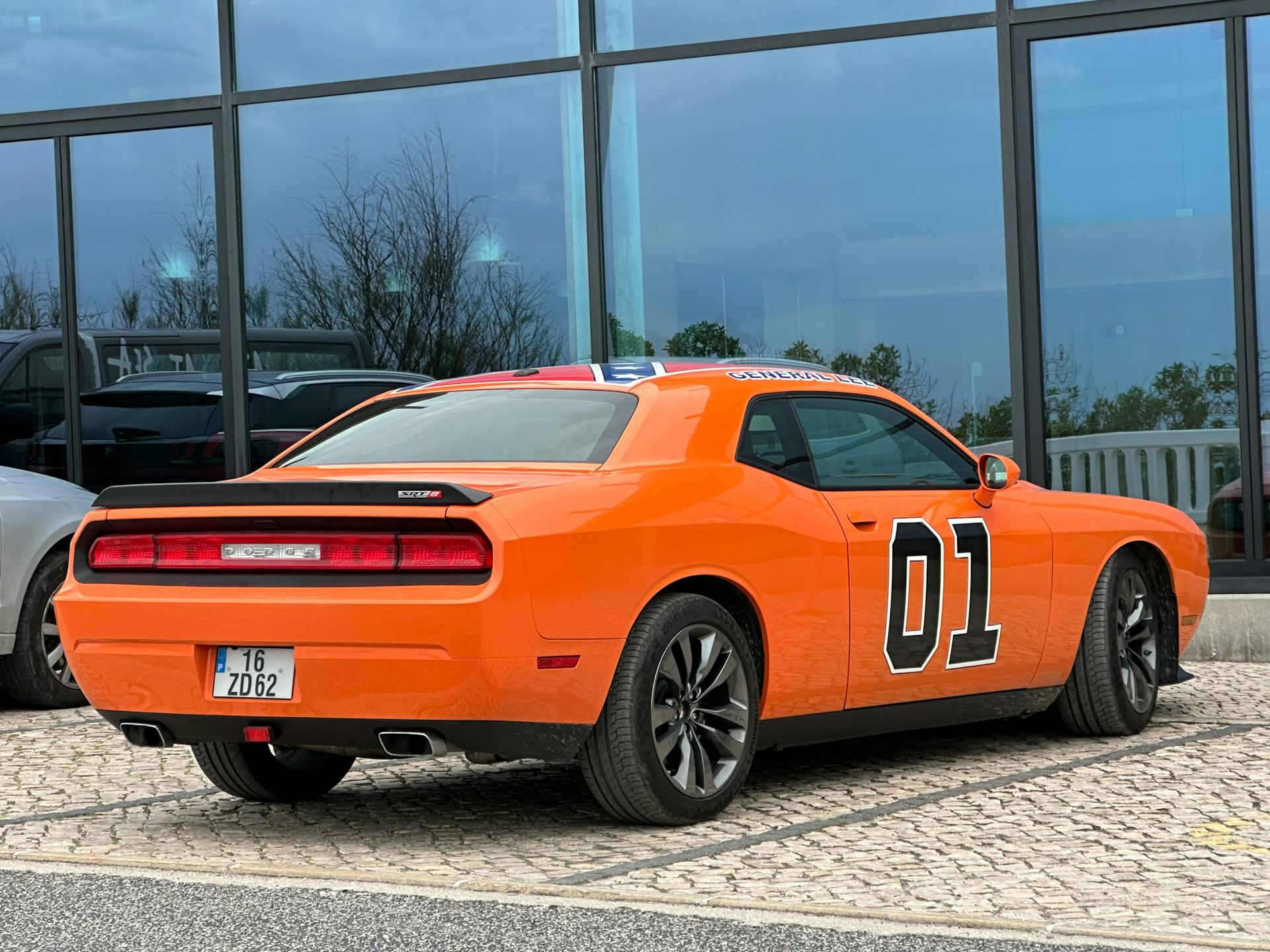 Bright orange car with iconic number 01 decal parked outside a building.