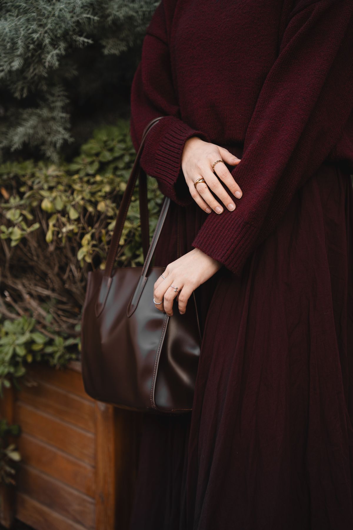 Burgundy Outfits for Women — 7 Wine Red Looks for Fall and Winter Woman in a maroon sweater outfit with a matching leather handbag