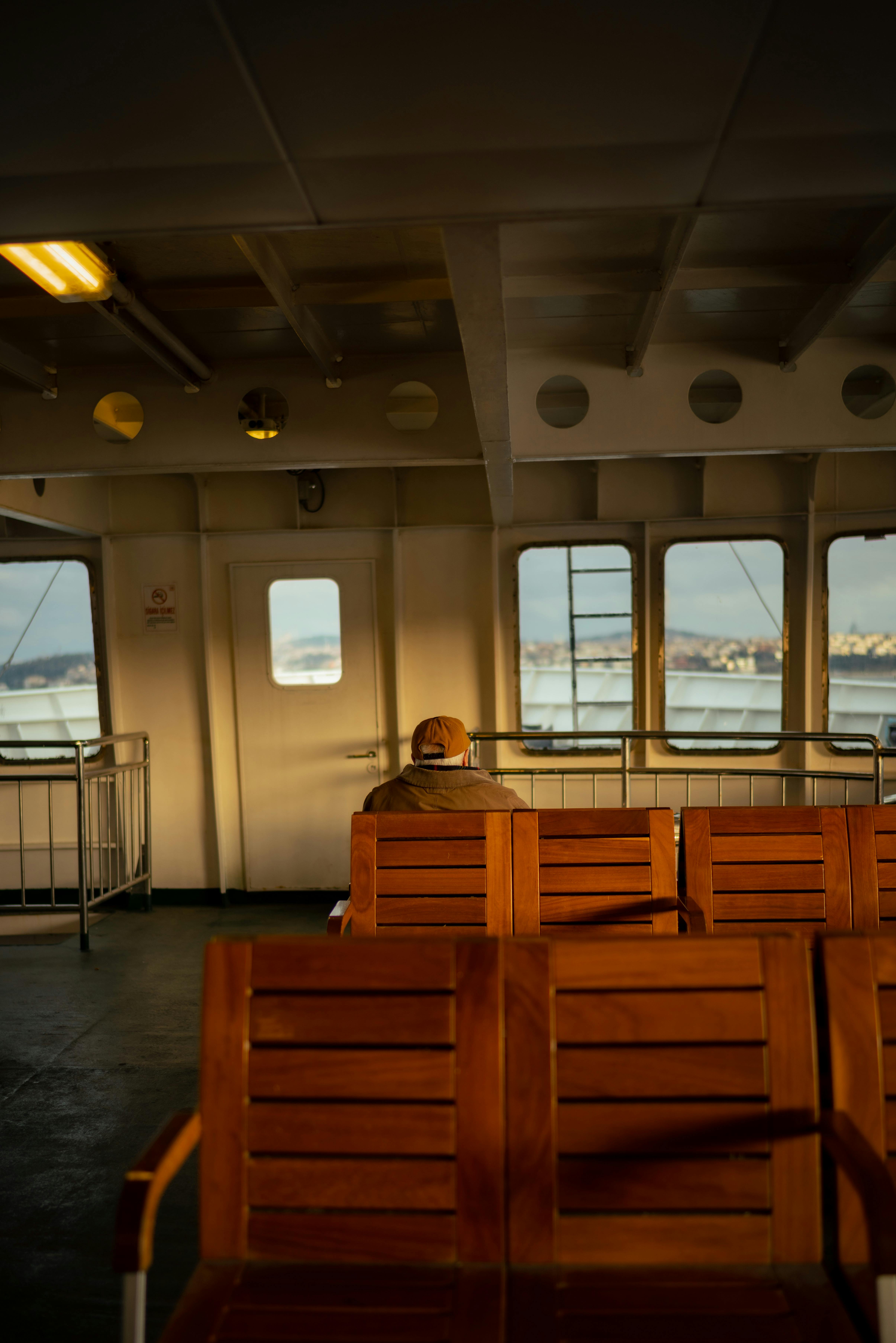 A lone traveler enjoys a serene ferry ride with scenic coastal views.