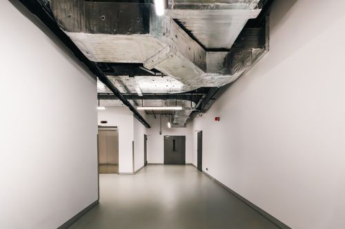 Free Spacious industrial hallway featuring exposed HVAC ductwork and modern design elements. Stock Photo
