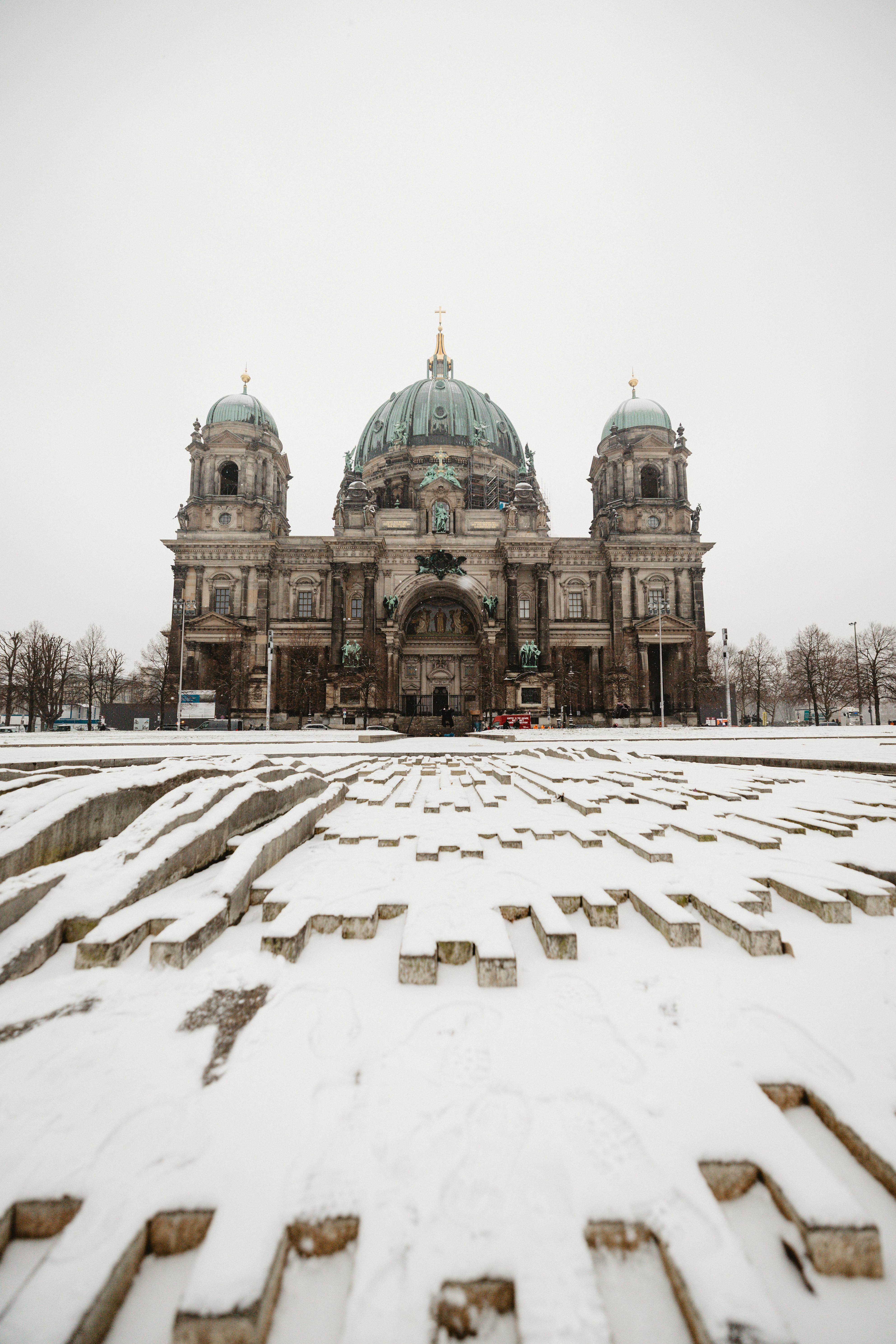 A tranquil winter view of Berlin Cathedral with a snow-covered foreground in Berlin, Germany.