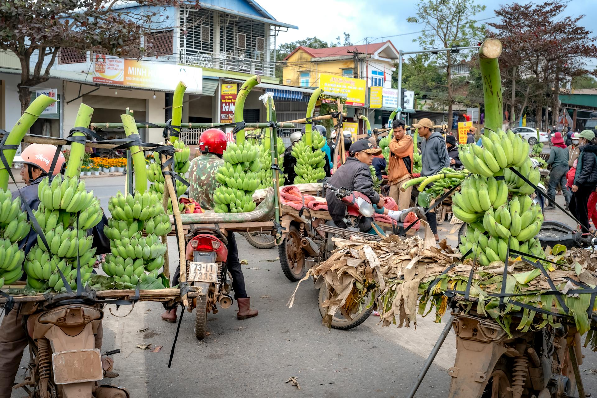 Bustling Southeast Asian market scene with motorcycles laden with fresh bananas.