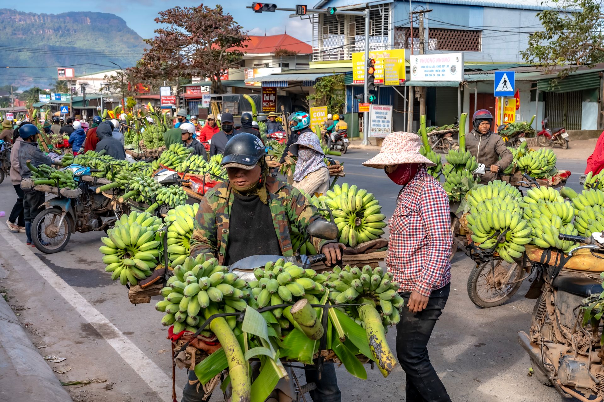 Motorbike vendors selling bananas on a busy street market with vibrant local activity.