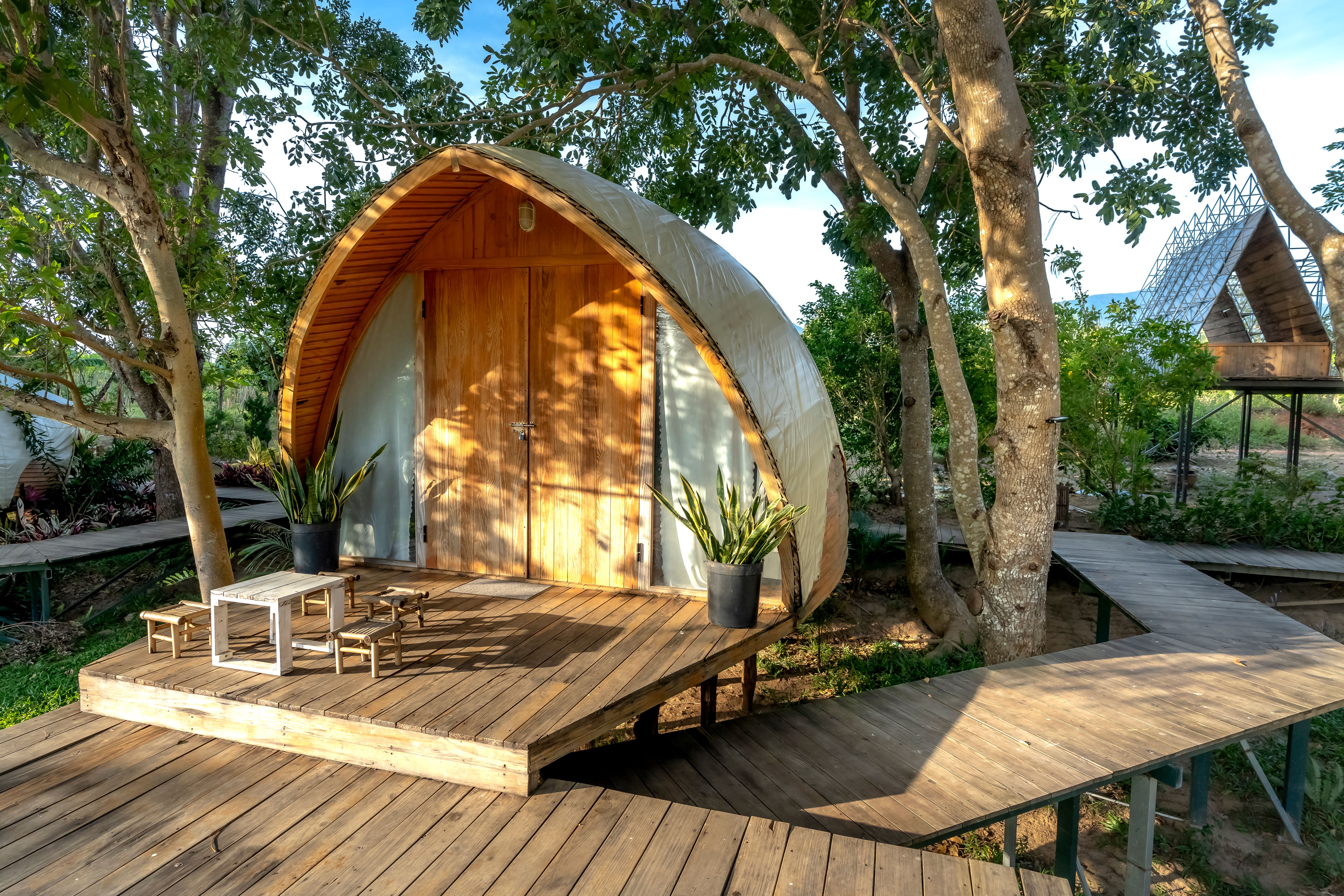 Studio en bois arrondi sur une terrasse au milieu des arbres