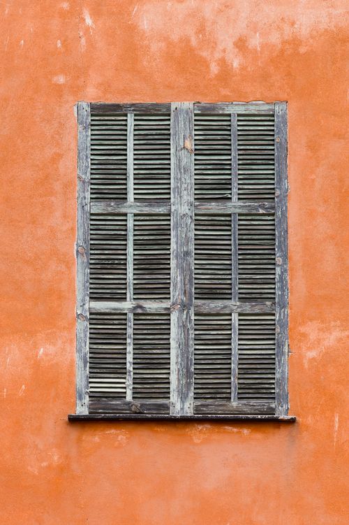 Free A vintage closed shuttered window on a vibrant orange wall in Menton, France. Stock Photo