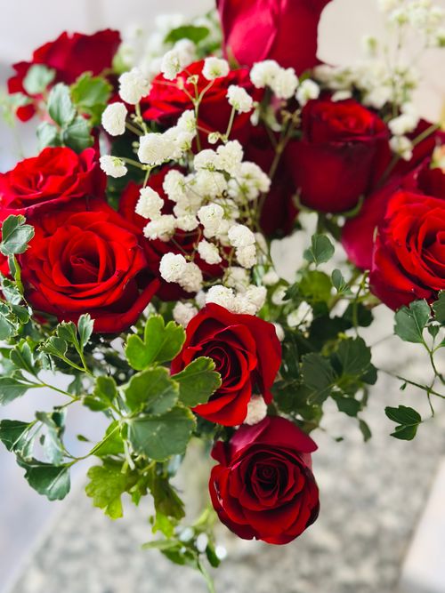 Free A stunning floral arrangement of vibrant red roses with delicate baby's breath. Stock Photo