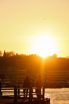 Dramatic sunset over Istanbul with silhouettes of people on a pier, capturing the city's enchanting skyline.