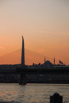 Golden sunset over İstanbul's iconic skyline with a silhouette of a city bridge.