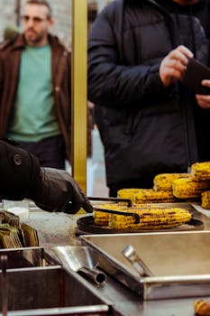 Close-up of a street vendor grilling corn on an outdoor stall, showcasing daily urban life.