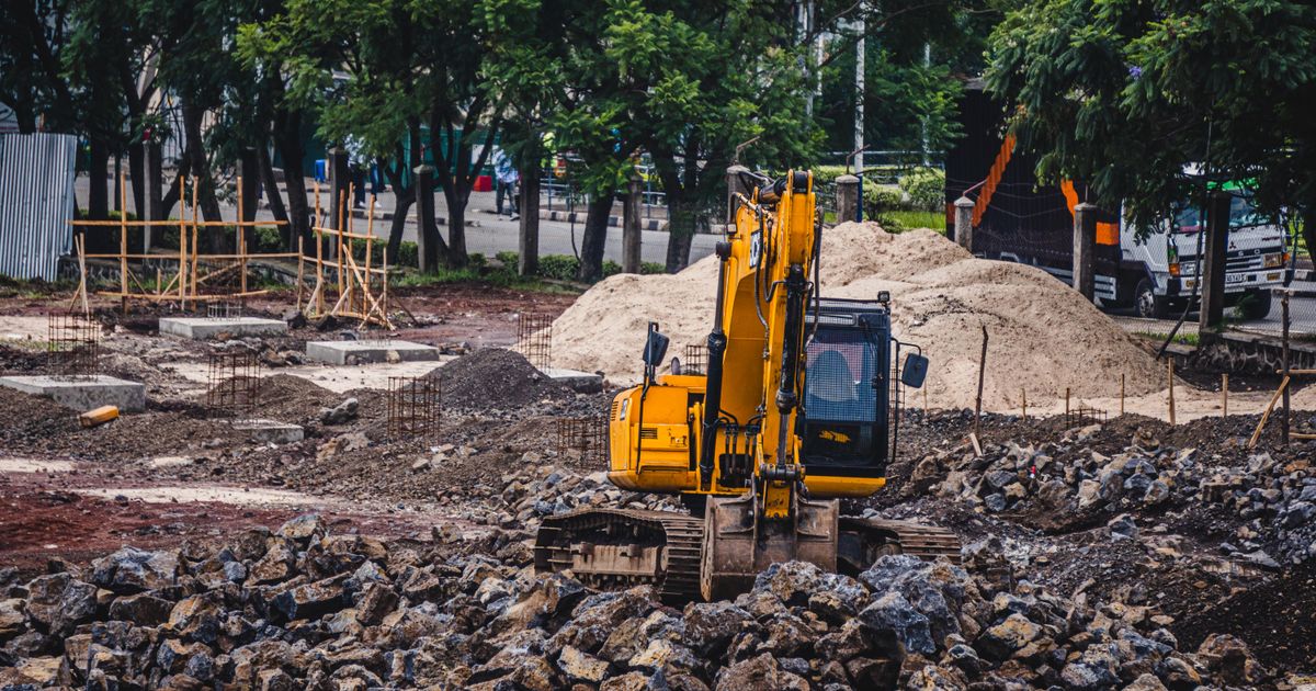 造成中の土地で黄色いショベルカーが土砂の山のそばで作業している