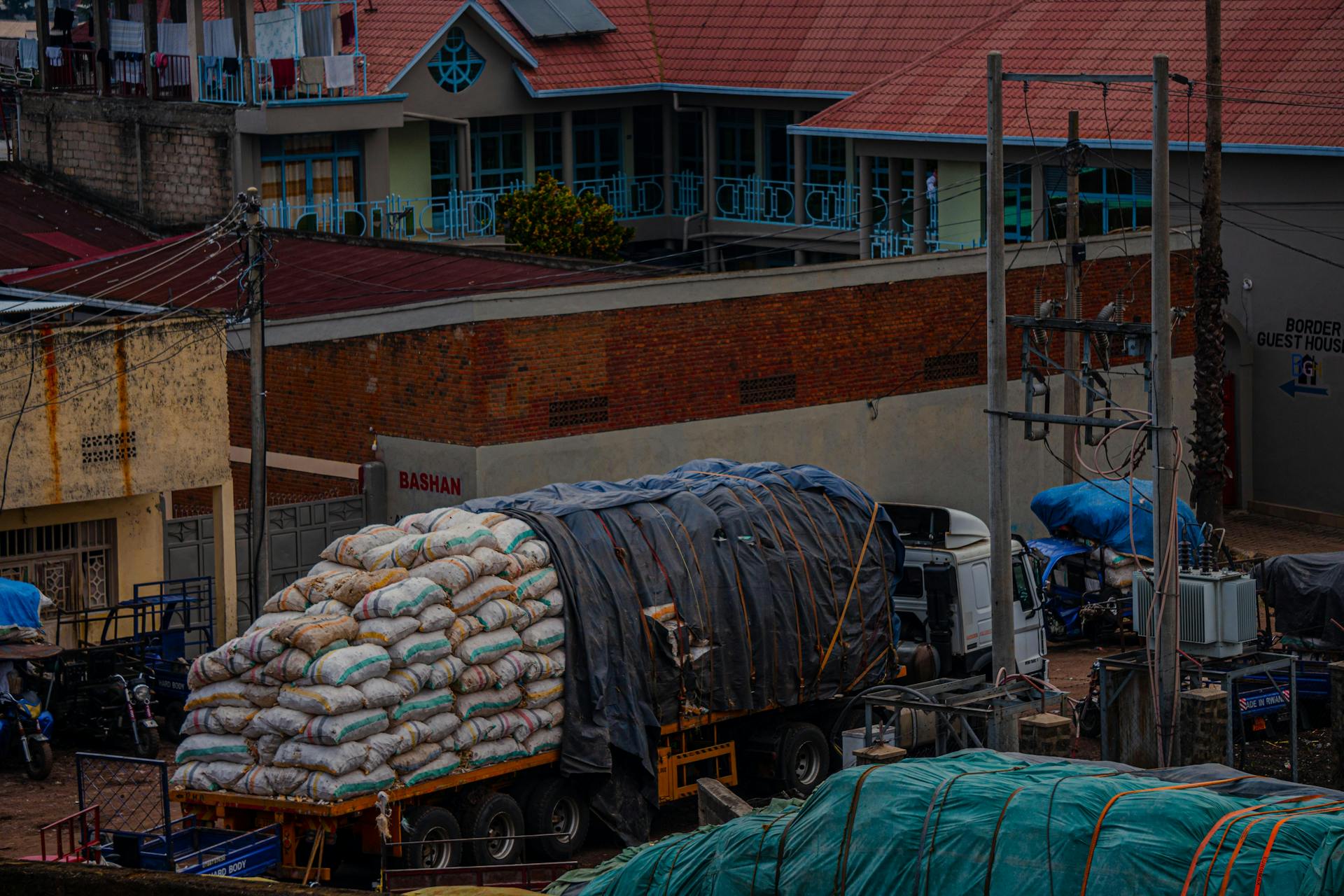 A cargo truck loaded with sacks parked in an urban area near a guest house.