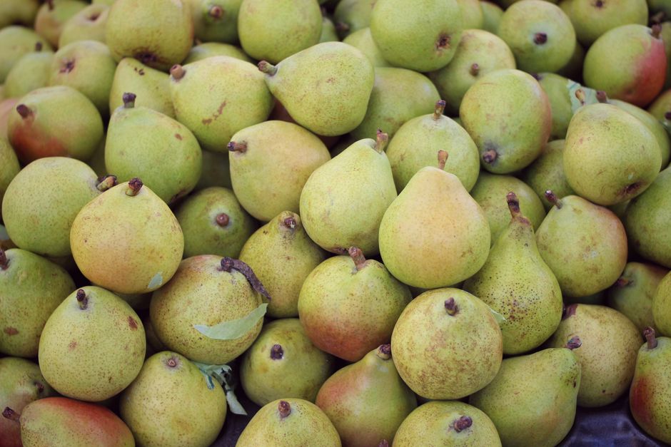 Peras frescas doradas en cesta de mimbre sobre fondo de mercado agrícola