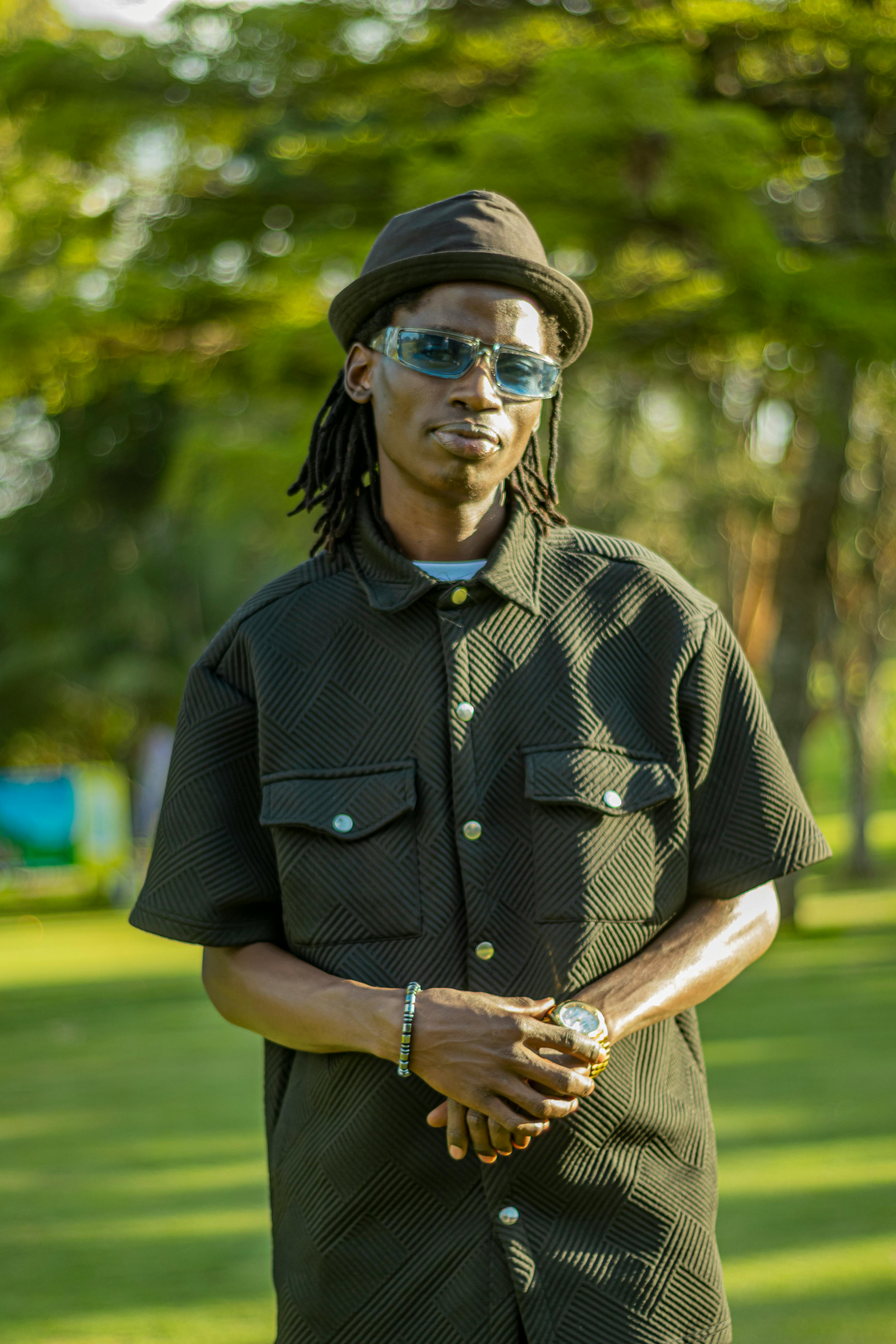 A stylish portrait of a male musician in Nairobi, Kenya, with green outdoor scenery.
