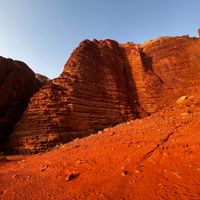 Layered red sandstone cliffs above a scree slope. Photo by Gyorgy Lakatos on Pexels