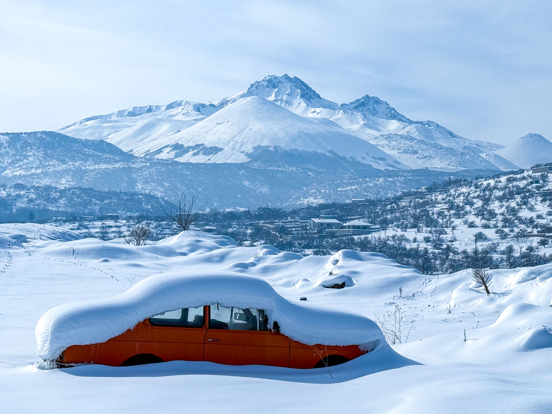 Schneebedecktes Fahrzeug vor einer weiten Berglandschaft.