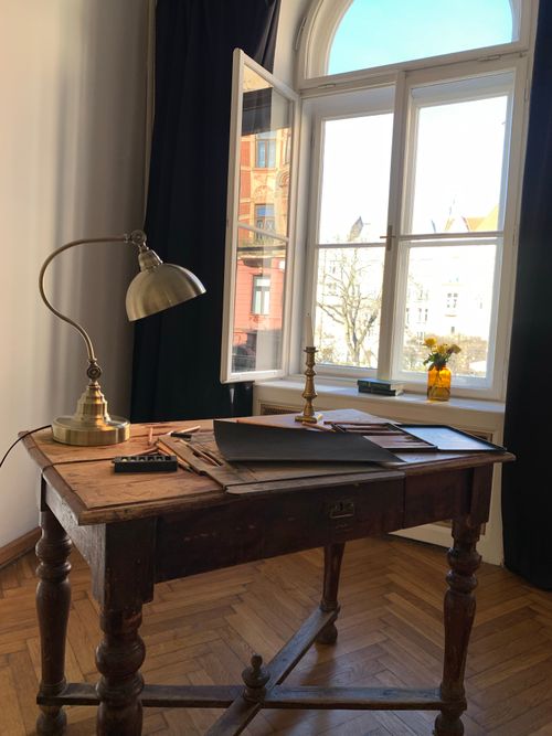 Free A rustic wooden desk with a lamp and papers by a sunny window. Stock Photo