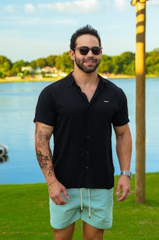 Smiling man with sunglasses enjoying a sunny day by the lake.