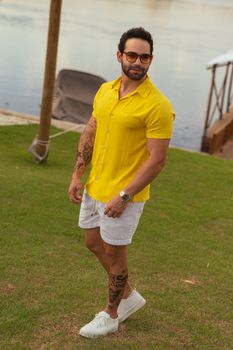 Athletic man in yellow shirt and shorts enjoying a sunny day by the water.