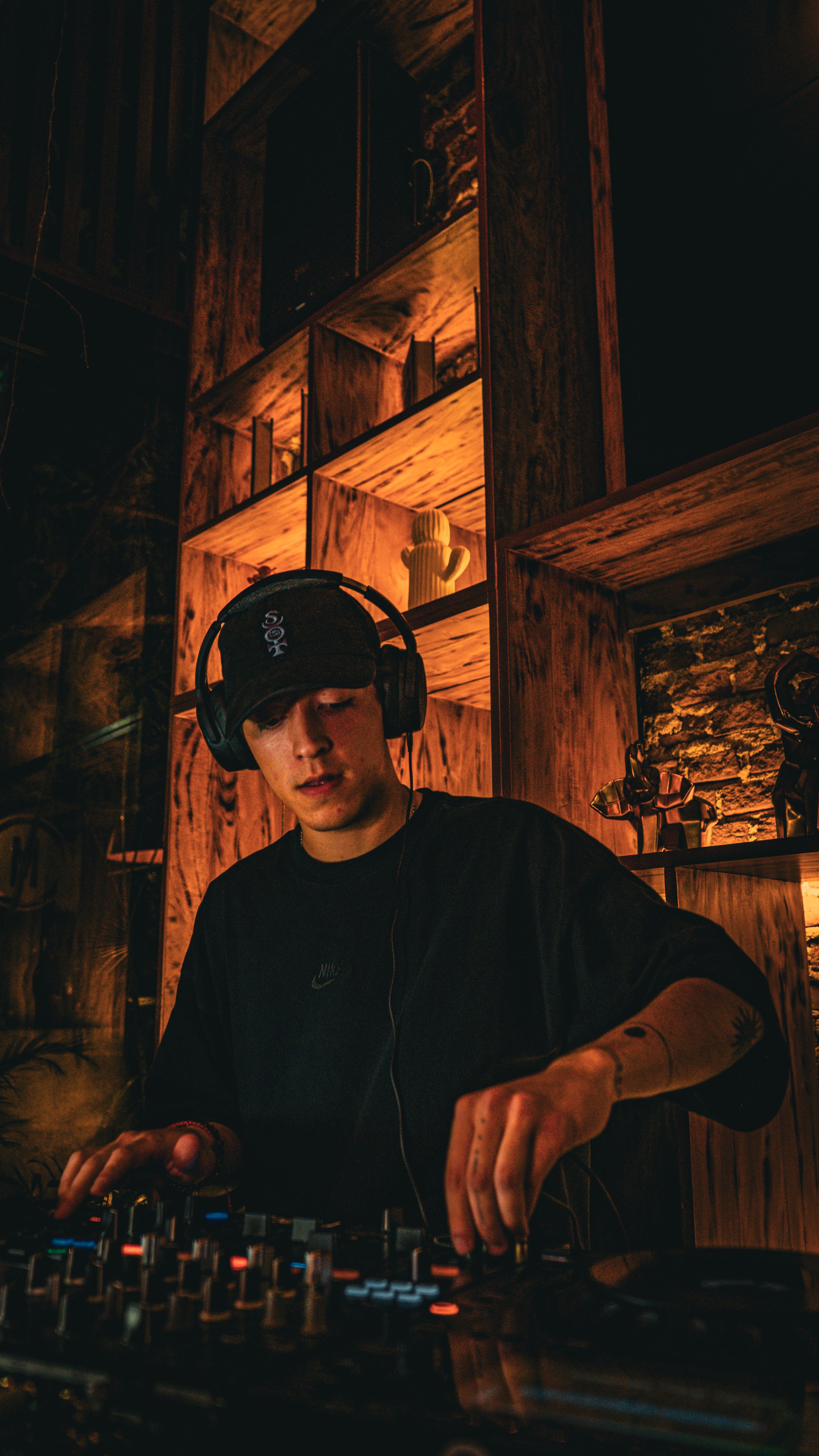 DJ mixing music at an indoor event with stylish ambience and warm lighting.