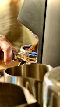 A barista prepares fresh coffee using a grinder in a cafe setting.