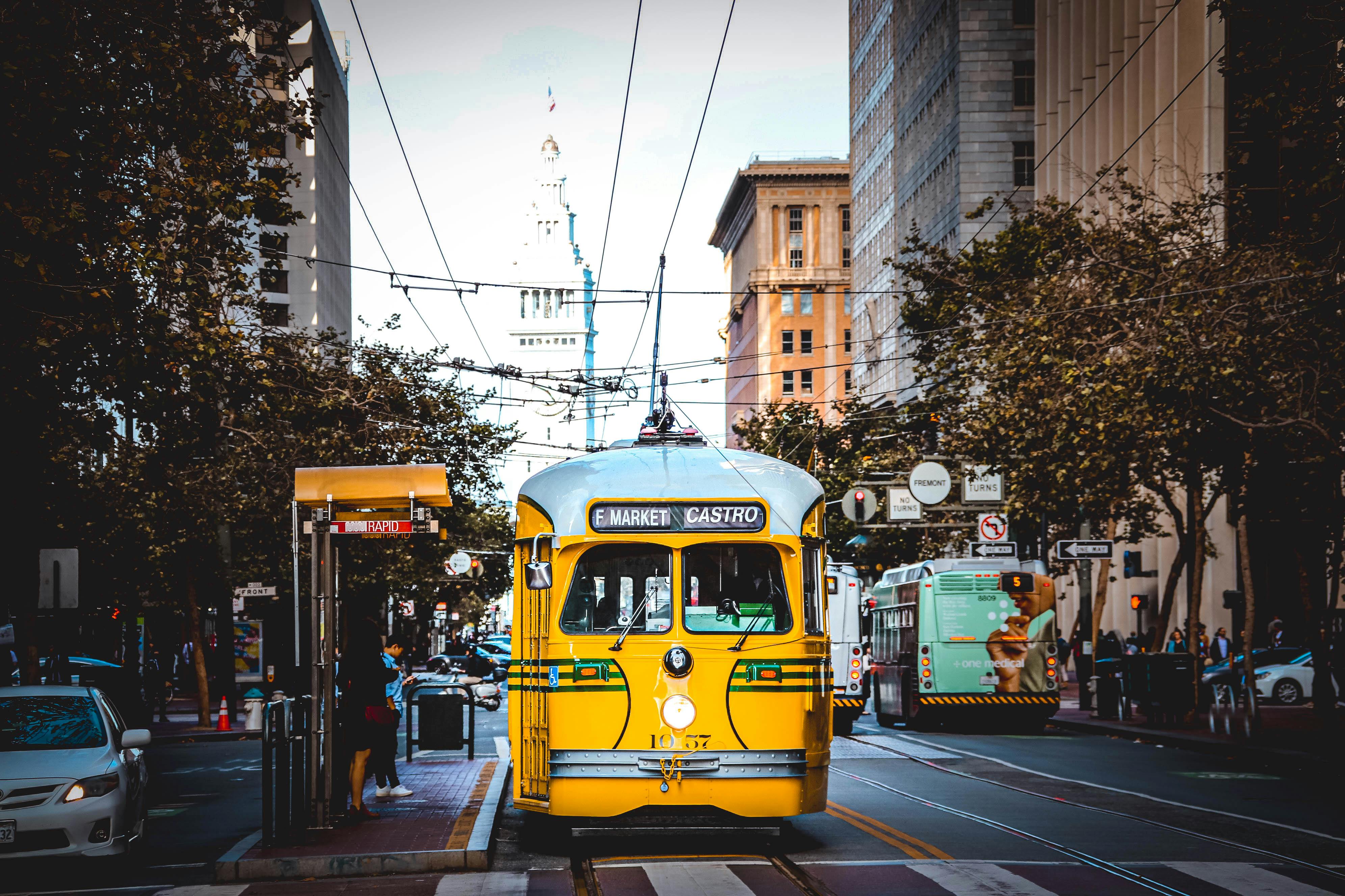 Classic yellow streetcar traveling through San Francisco on a bustling day.