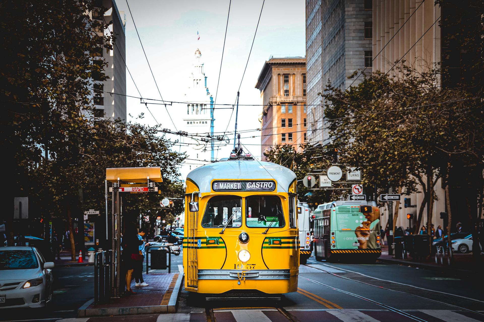 Classic yellow streetcar traveling through San Francisco on a bustling day.