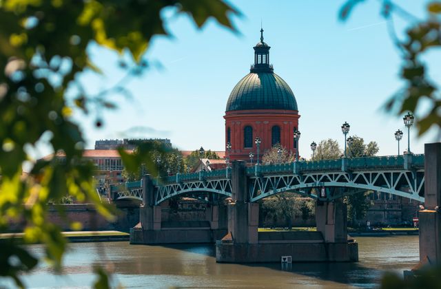 Scenic view of Pont Saint-Pierre and red dome in Toulouse, France framed by leaves. — arriving in Toulouse/Blagnac
