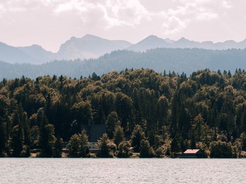 Free Tranquil scene of mountains, forest, and lake under a cloudy sky. Stock Photo