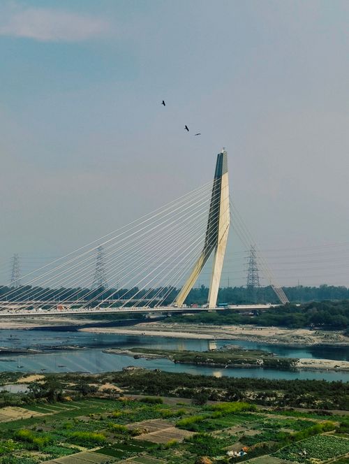Free A striking cable-stayed bridge spans across a calm river with a clear sky above. Stock Photo