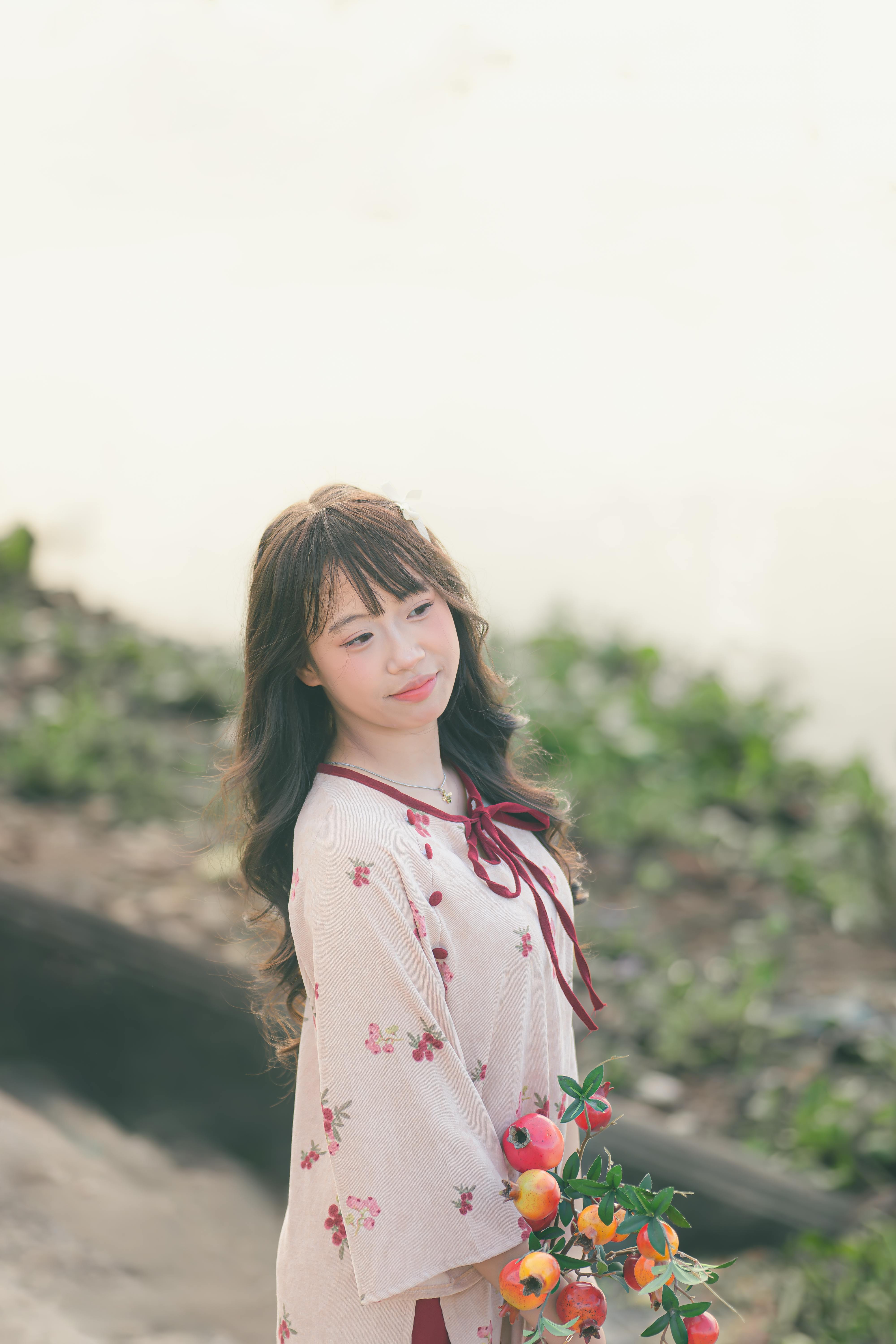 young woman with vegetables in floral dress outdoors